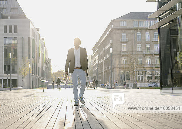 Businessman walking in the city at sunset