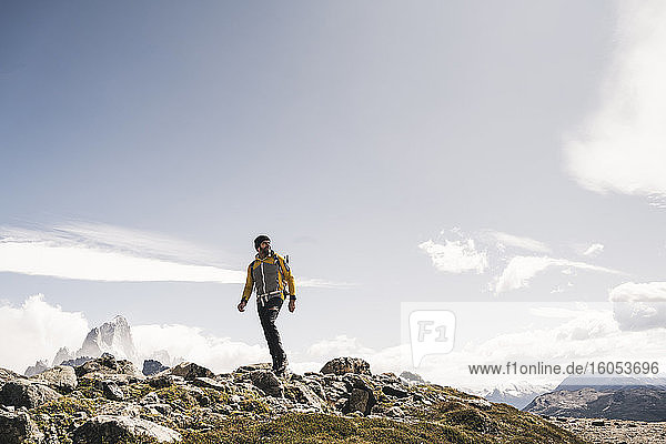 Älterer Mann mit Rucksack  der an einem sonnigen Tag auf einem Berg gegen den Himmel läuft  Patagonien  Argentinien