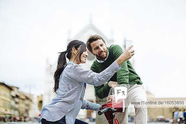 Frau macht Selfie mit ihrem Freund auf einer Vespa in Florenz  Italien
