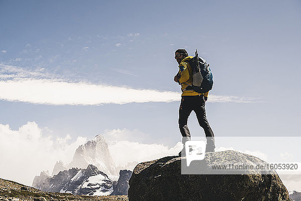Männlicher Wanderer mit Rucksack auf einem Felsen stehend gegen den Himmel an einem sonnigen Tag  Patagonien  Argentinien