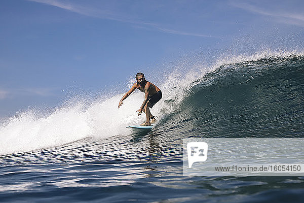 Shirtless mid adult man surfing on sea against sky  Bali  Indonesia
