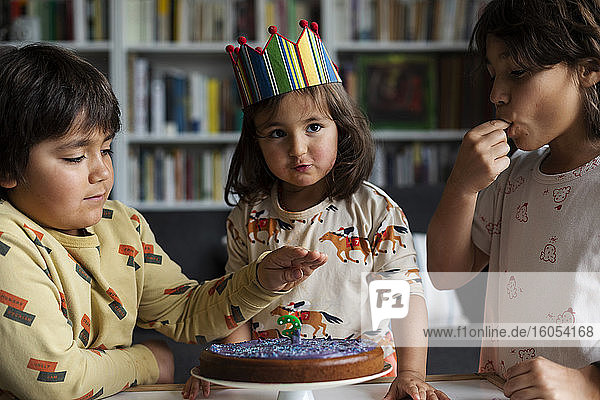Porträt eines kleinen Mädchens  das seinen Geburtstag mit seinen älteren Brüdern zu Hause feiert