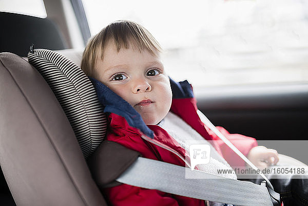 Nahaufnahme eines niedlichen kleinen Jungen  der auf einem Autositz sitzt