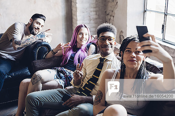 Group of friends sitting on sofa in a lofttaking a selfie