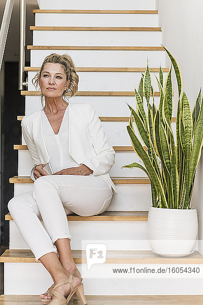 Portrait of mature businesswoman sitting on stairs looking at distance