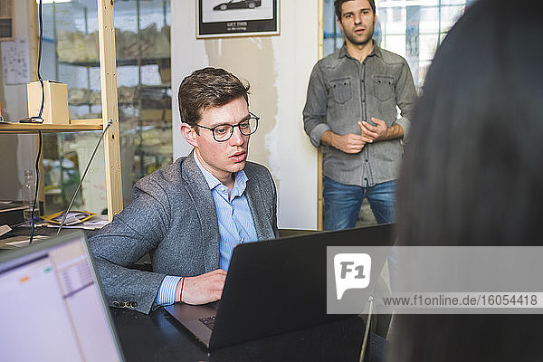 Drei Geschäftsleute mit Laptop bei einem Treffen im Büro