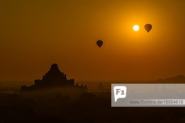 Myanmar  Mandalay Region  Bagan  Silhouettes of hot air balloons flying over ancient temples at foggy dawn