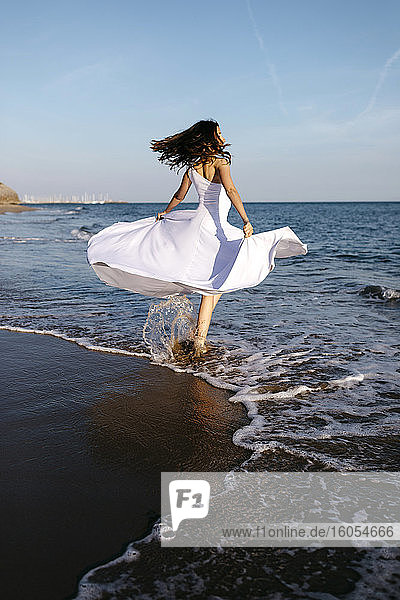 Ballerina im weißen Kleid tanzt am Meer