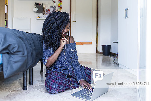 Junge Frau mit Laptop und Kopfhörern zu Hause