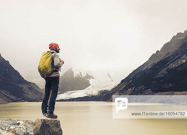 Mature man with backpack standing on rock by lake at Patagonia  Argentina