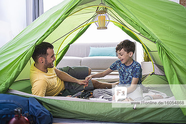 Father and son sitting in tent at home