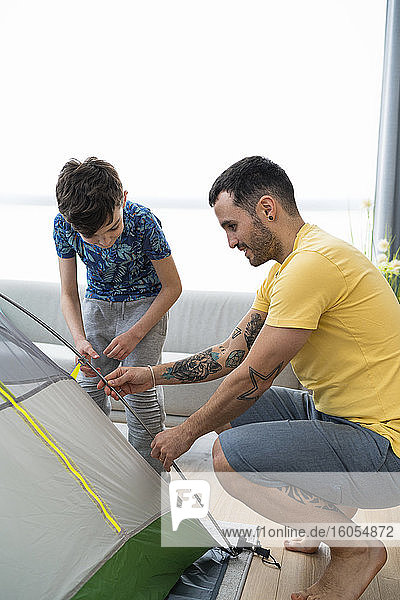 Father and son putting up tent at home