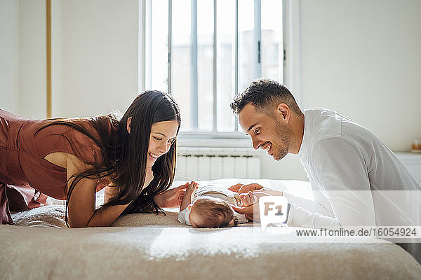 Happy parents playing with baby boy in bedroom at home