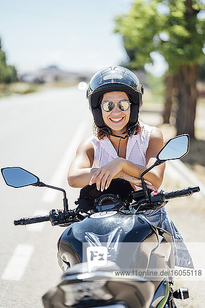 Female biker with sunglasses sitting on motorbike