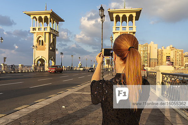 Ägypten  Alexandria  Rückansicht einer Frau  die die Stanley-Brücke bei Sonnenuntergang fotografiert