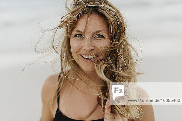Nahaufnahme einer glücklichen Frau mit zerzaustem Haar am Meer