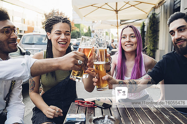 Glückliche Freunde stoßen an einer Bar im Freien mit Biergläsern an