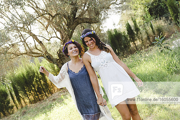 Happy female friends wearing wreaths while walking at yard