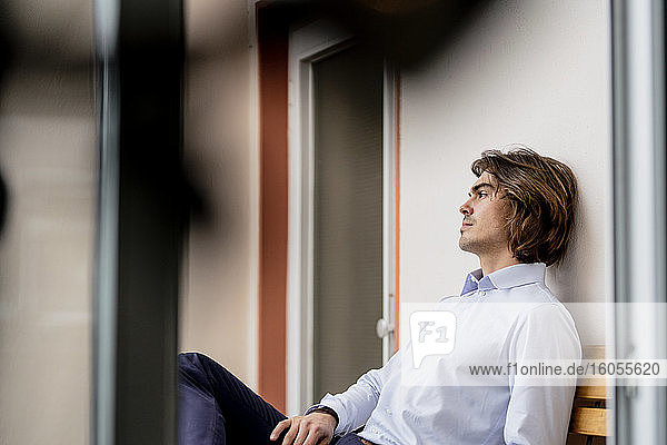 Nachdenklicher Geschäftsmann sitzt auf einem Stuhl an der Wand eines Cafés