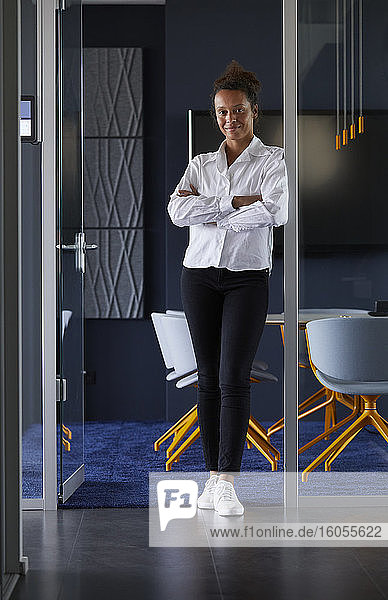 Porträt einer lächelnden Geschäftsfrau  die im Sitzungssaal eines modernen Büros steht