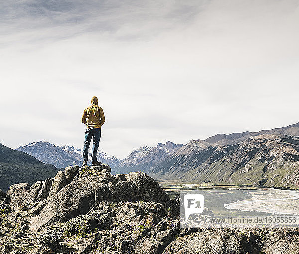 Mature man wearing hood looking at mountains against sky while standing on rock  Patagonia  Argentina