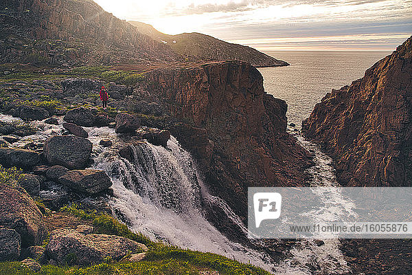 Frau steht auf einem Felsen am Wasserfall  Teriberka  Gebiet Murmansk  Russland