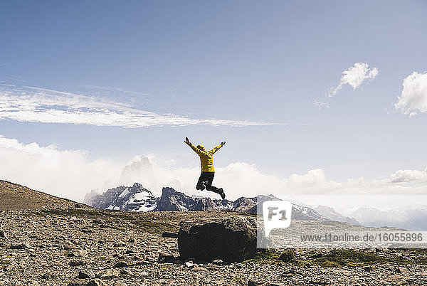 Carefree mature man jumping on rock against sky  Patagonia  Argentina