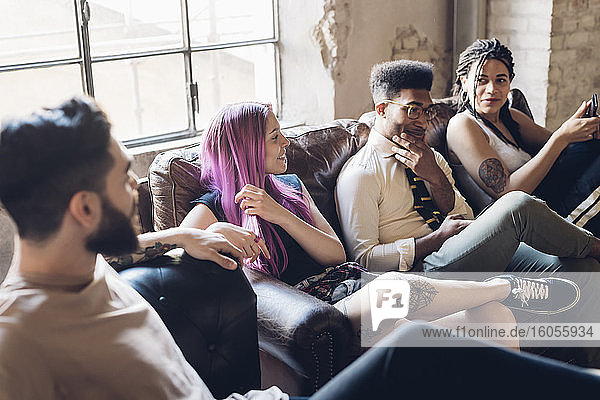 Gruppe von Freunden sitzt auf einem Sofa in einem Loft