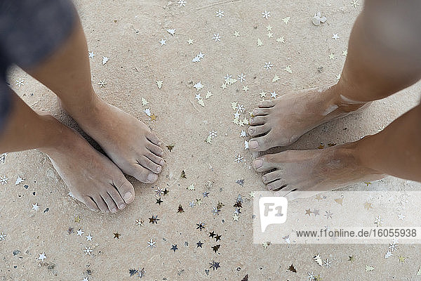 Female friends standing with Christmas confetti on sand