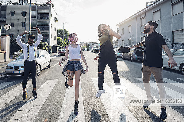 Gruppe sorgloser Freunde  die auf einer Straße in der Stadt springen