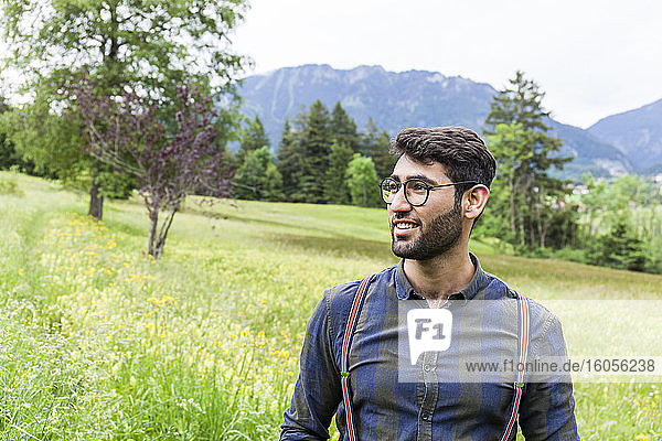 Porträt eines lächelnden jungen Mannes auf einer Wiese  Reichenwies  Oberammergau  Deutschland