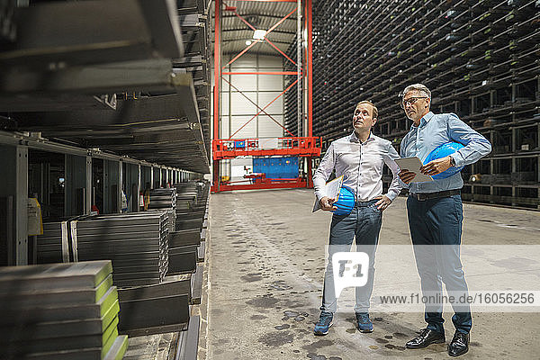 Zwei Geschäftsleute bei einem Treffen in einem Hochregallager einer Fabrik