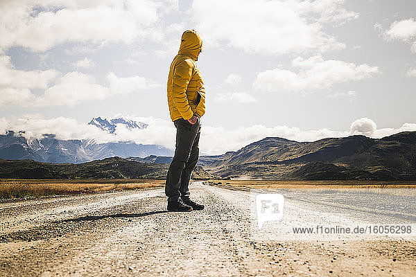 Mature man standing on dirt road against cloudy sky  Torres Del Paine National Park  Patagonia  Chile