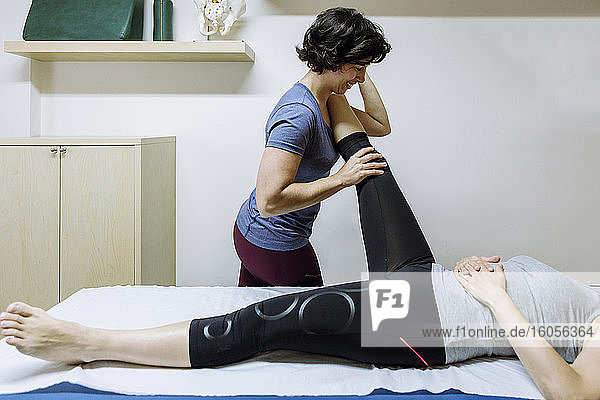 Female physiotherapist stretching leg of client