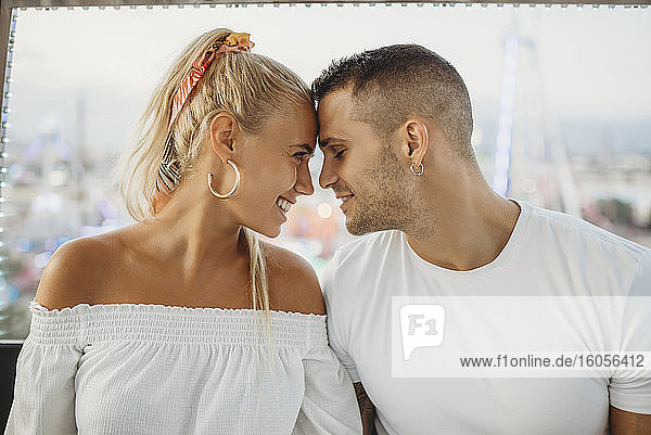 Close-up of romantic couple with face to face sitting in Ferris wheel