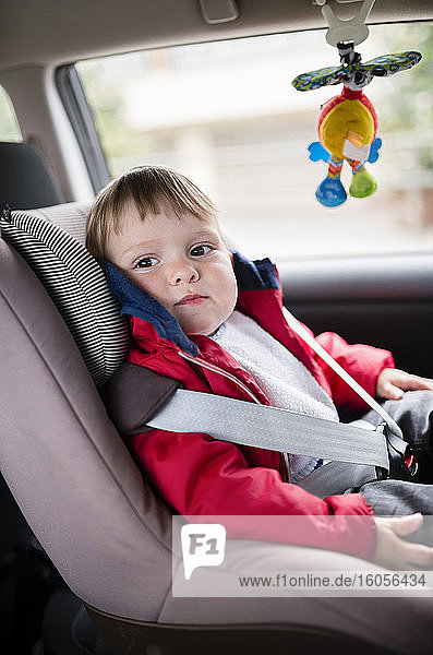 Niedlicher Babyjunge schaut weg  während er auf dem Autositz sitzt