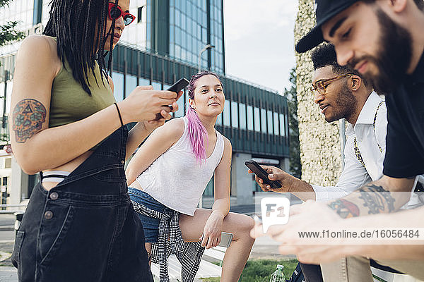 Eine Gruppe von Freunden benutzt Smartphones in der Stadt