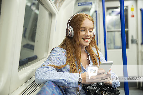 Schöne junge Frau hört Musik  während sie im Zug sitzt