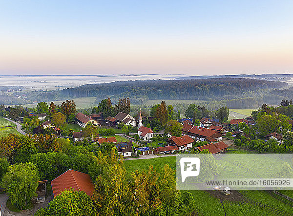 Deutschland  Bayern  Walchstadt  Drohnenansicht eines Dorfes auf dem Land bei nebligem Sonnenaufgang