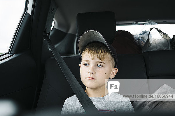 Cute boy looking away while sitting in car