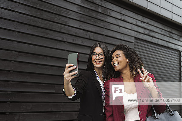 Beautiful businesswoman taking selfie with female colleague in city