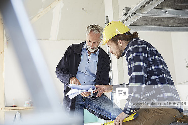 Architect and worker discussing building plan on a construction site