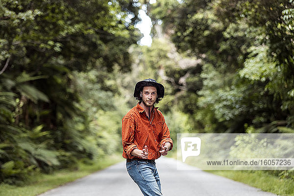 Selbstbewusster junger Mann  der auf einer Straße im Wald steht und gestikuliert