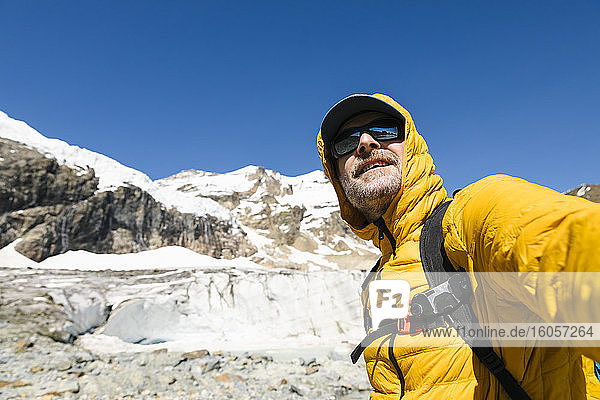 Lächelnder reifer Mann  der vor einem schneebedeckten Berg steht