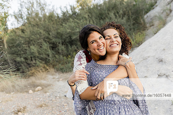 Happy young woman embracing female friend at countryside