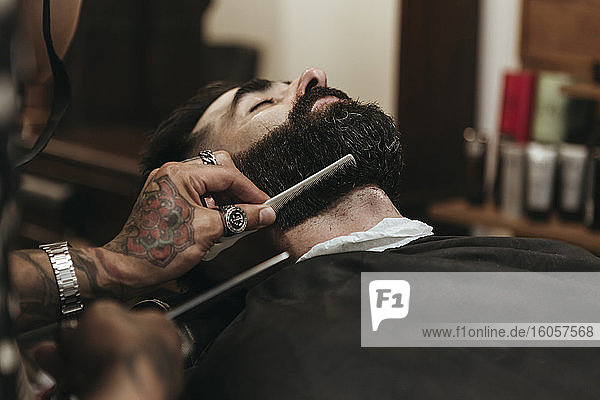 Barber combing client's beard at salon