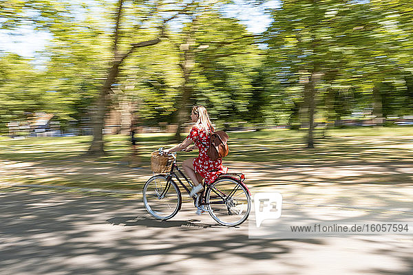 Unscharfe Bewegung einer Frau beim Fahrradfahren auf dem Fußweg im Park