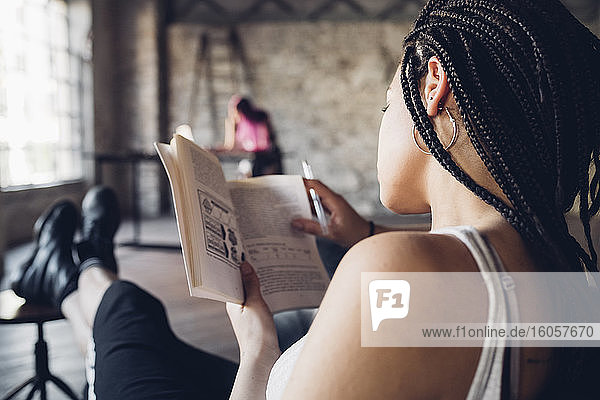 Young woman reading a book in loft office