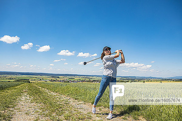 Junge Frau spielt Golf auf dem Lande