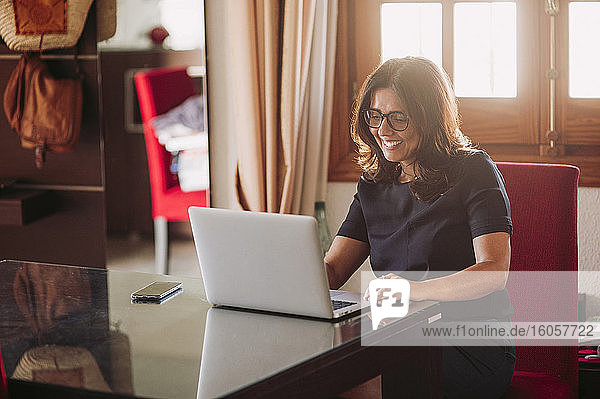 Smiling beautiful businesswoman working at home while using laptop in living room